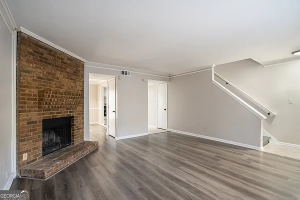 a view of an empty room with wooden floor fireplace and a window