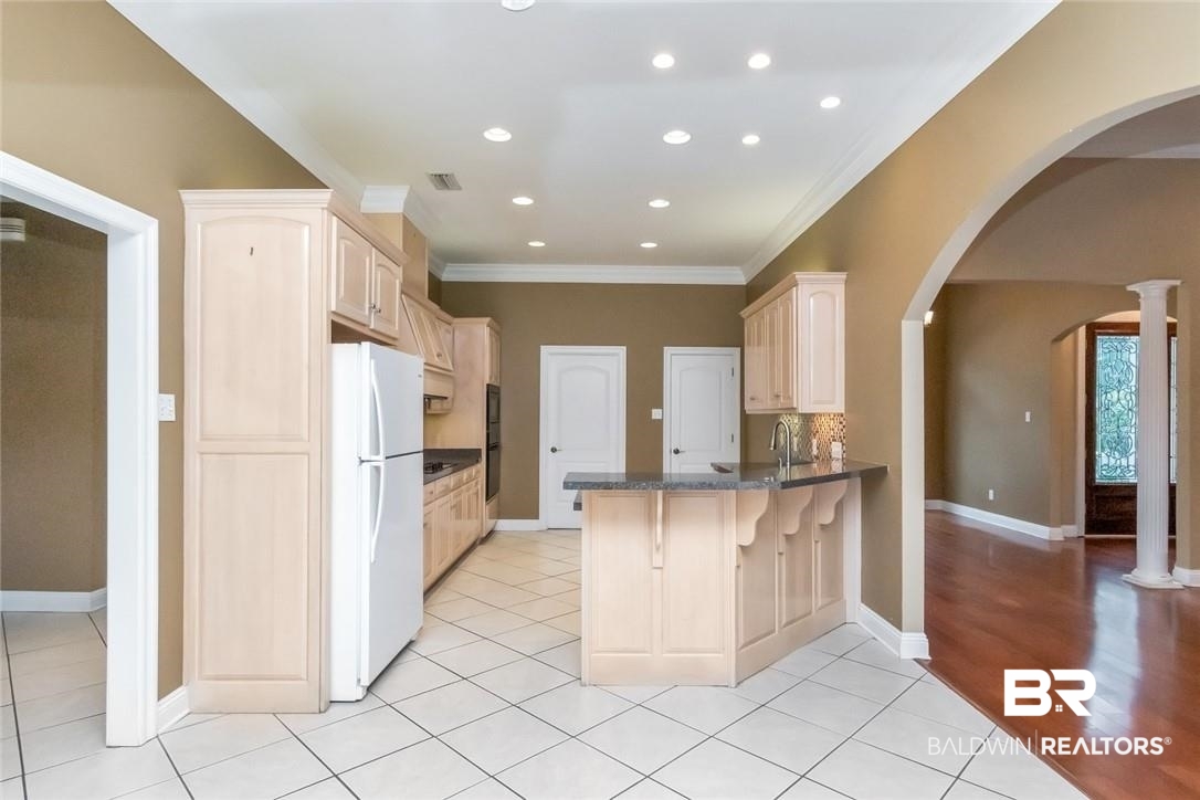 8837 Dawes Lake Road South Mobile, AL 36619 - Photo 26 of 44 Kitchen with light brown cabinetry, kitchen peninsula, decorative columns, and white fridge