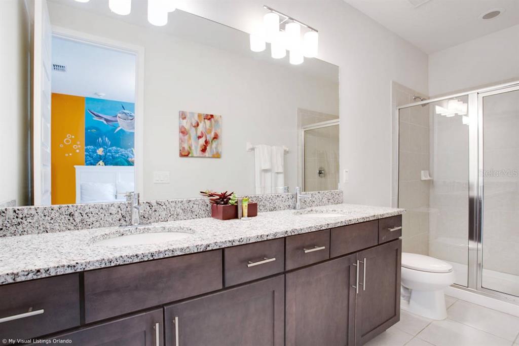 7736 Graben Street Kissimmee, FL 34747 - Photo 23 of 62 a bathroom with a granite countertop sink a toilet and a mirror