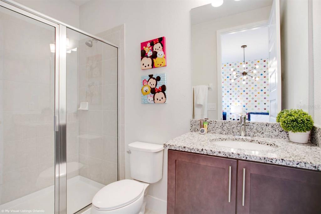 7736 Graben Street Kissimmee, FL 34747 - Photo 28 of 62 a bathroom with a granite countertop sink mirror vanity and toilet