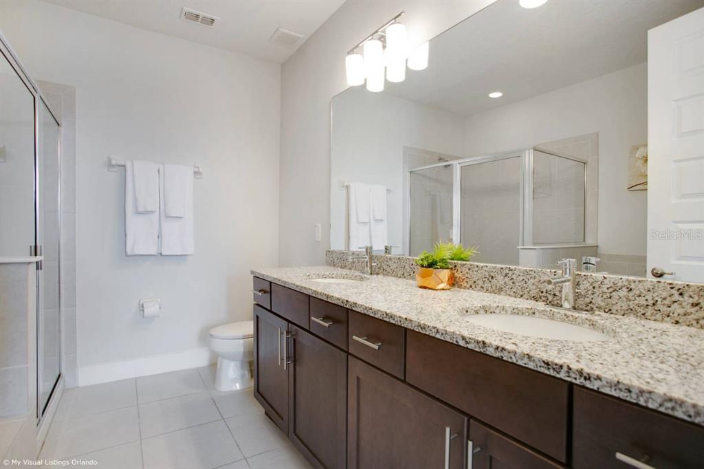 7736 Graben Street Kissimmee, FL 34747 - Photo 29 of 62 a bathroom with a granite countertop sink a toilet and a mirror