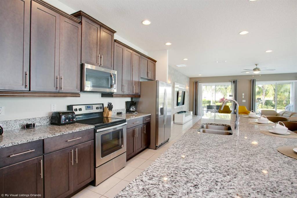 7736 Graben Street Kissimmee, FL 34747 - Photo 42 of 62 a kitchen with stainless steel appliances granite countertop a stove top oven a sink dishwasher and white cabinets