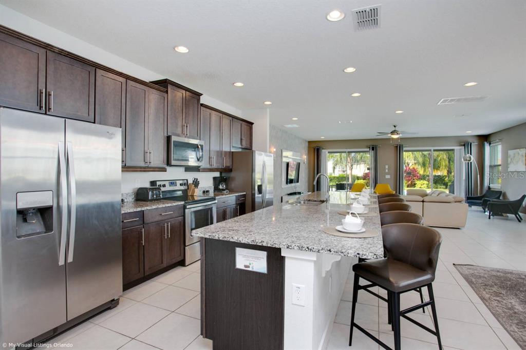 7736 Graben Street Kissimmee, FL 34747 - Photo 52 of 62 a kitchen with stainless steel appliances granite countertop a refrigerator a stove a sink a dining table and chairs