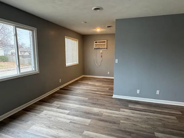 a view of an empty room with wooden floor and a window