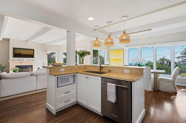 a view of a kitchen counter top space with sink stainless steel appliances and wooden floor