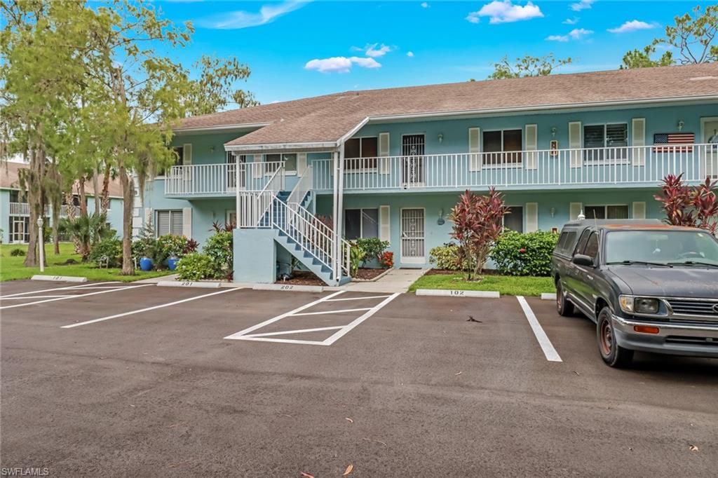 5675 Whitaker Road, Unit B202 Naples, FL 34112 - Photo 1 of 26 a front view of a house with a yard and parking space