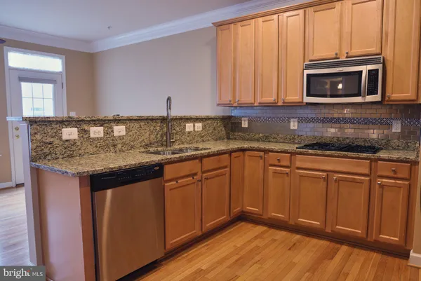 a kitchen with granite countertop cabinets stainless steel appliances a sink and wooden floor