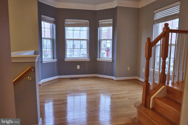 a view of an empty room with glass door and wooden floor