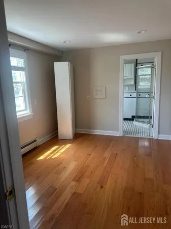 an empty room with wooden floor cabinet and windows