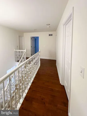 a view of a hallway with wooden floor and stairs
