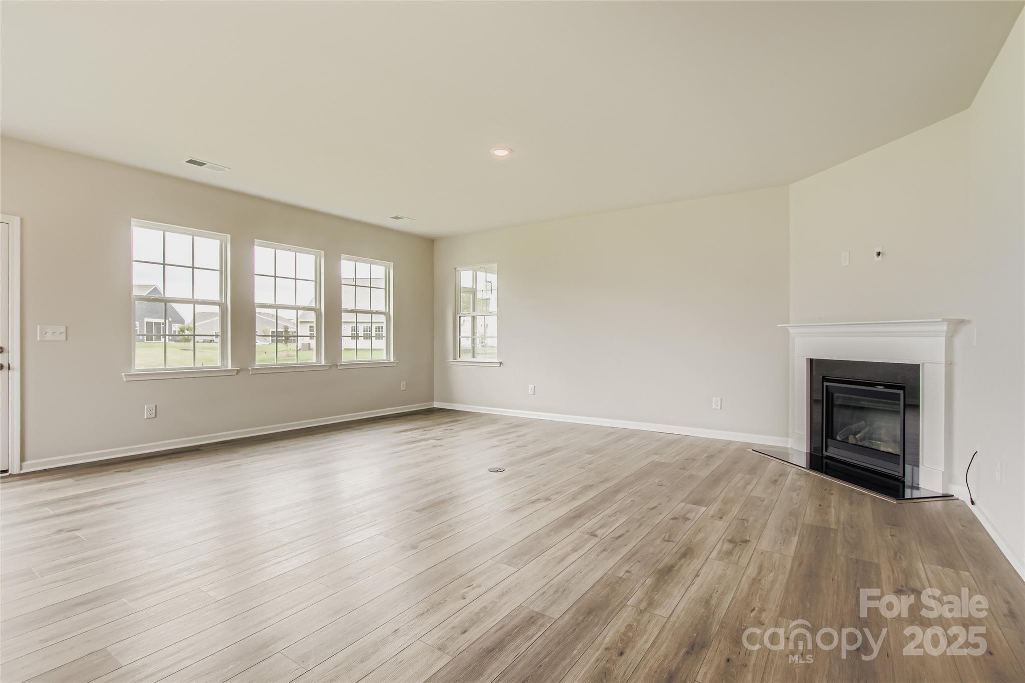 2803 Morning Song Way Lancaster, SC 29720 - Photo 4 of 18 an empty room with wooden floor fireplace and windows