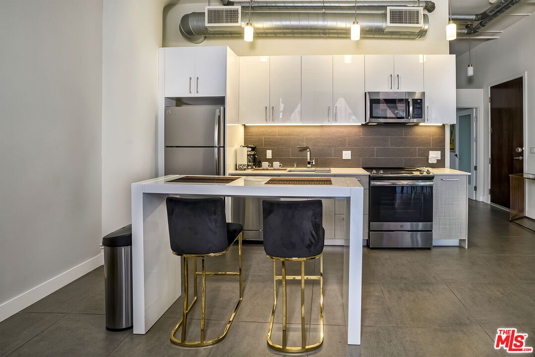 939 South Broadway, Unit 304 Los Angeles, CA 90015 - Photo 4 of 21 a kitchen with stainless steel appliances granite countertop a stove a refrigerator and a sink