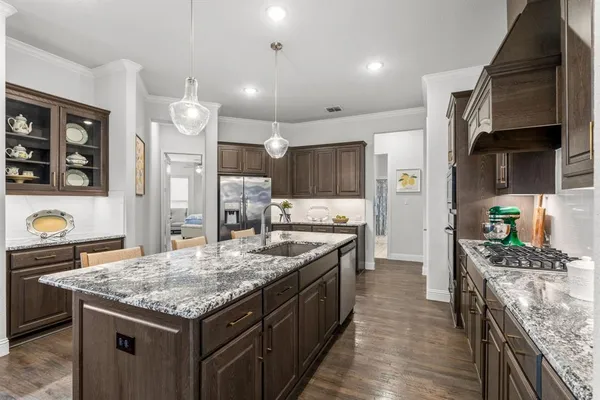 a kitchen with granite countertop kitchen island stainless steel appliances a sink stove and refrigerator