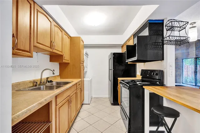 a kitchen with stainless steel appliances kitchen island granite countertop a refrigerator a stove a sink a dining table and chairs with wooden floor