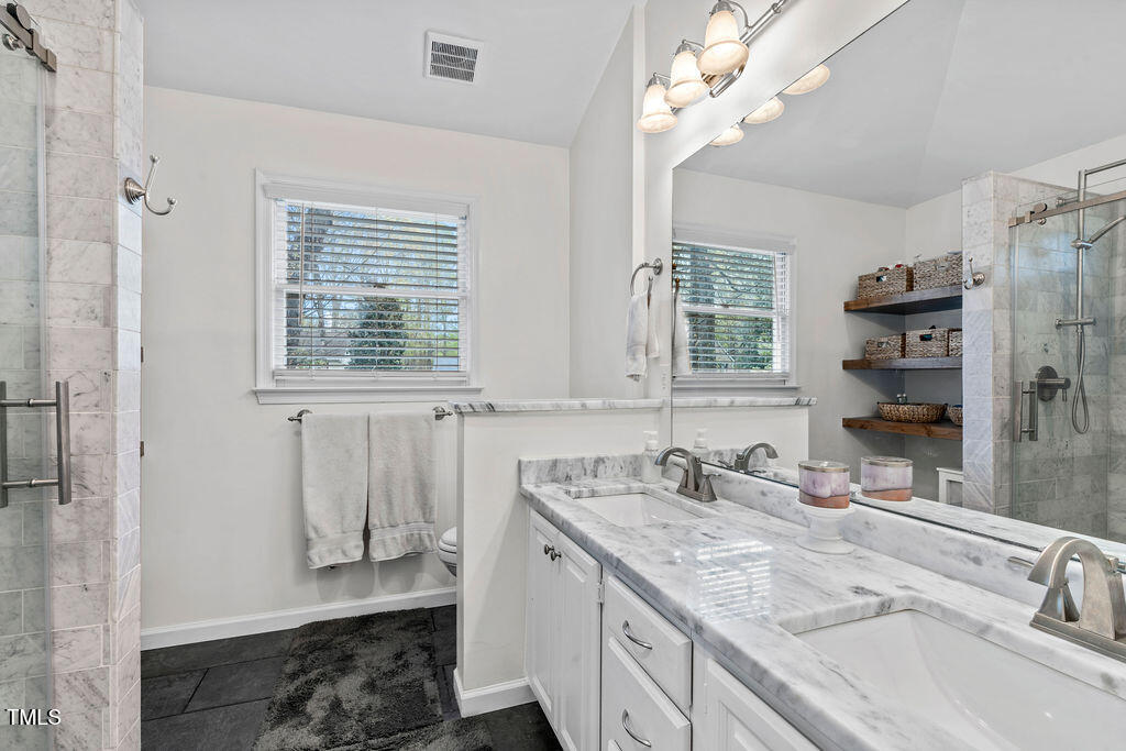 112 Oxpens Road Cary, NC 27513 - Photo 25 of 37 a bathroom with a granite countertop sink a mirror and a shower