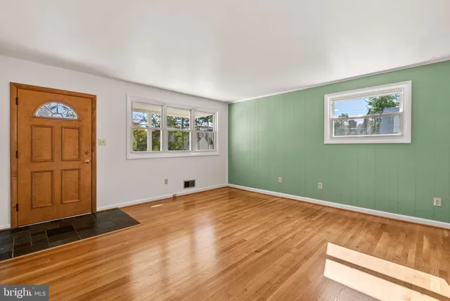 a view of an empty room with window and wooden floor