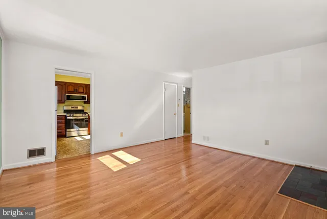 an empty room with wooden floor closet and windows
