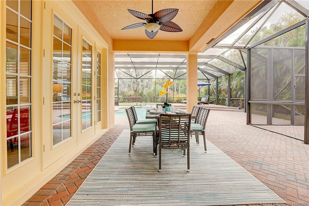 7426 Southeast Laque Circle Stuart, FL 34997 - Photo 13 of 81 a dining room with wooden floor a chandelier a glass table and chairs