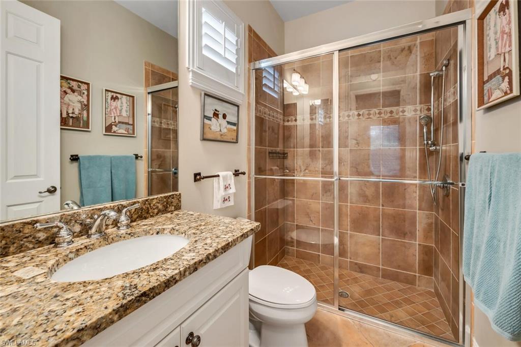 4956 Rustic Oaks Circle Naples, FL 34105 - Photo 18 of 37 a bathroom with a granite countertop sink a toilet a mirror and shower