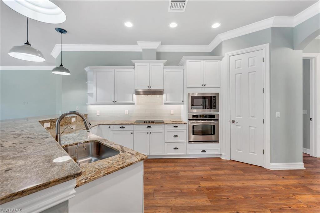 4956 Rustic Oaks Circle Naples, FL 34105 - Photo 8 of 37 a kitchen with granite countertop a sink stainless steel appliances and cabinets