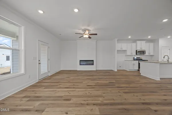 a view of an empty room with a window and wooden floor