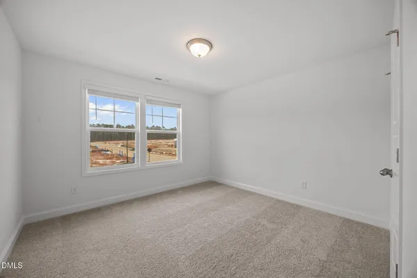a view of a white house next to a yard with wooden fence
