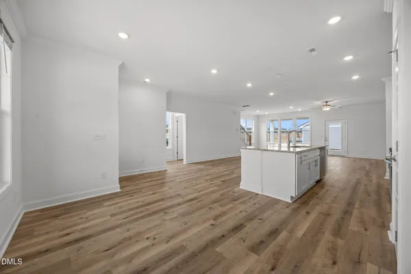 a view of empty room with wooden floor and kitchen