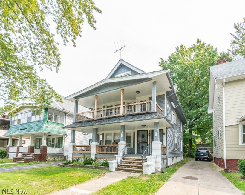 View of front of house with a porch, a front yard, and driveway