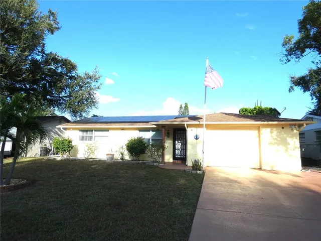a view of a house with a yard and a large tree