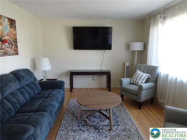 a living room with furniture a flat screen tv and a window