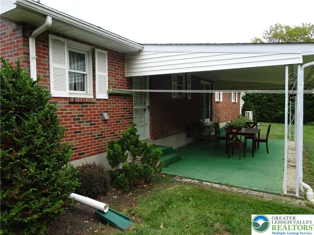 a backyard of a house with table and chairs floor to ceiling window and a yard