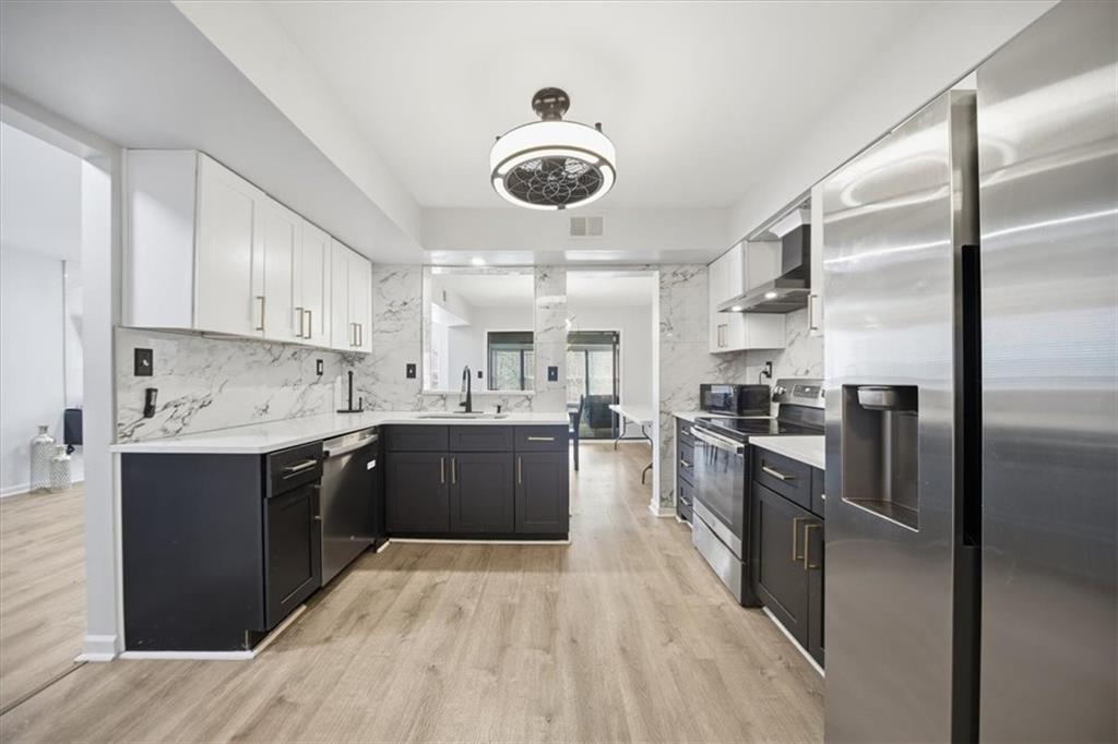 1039 Mariners Court Stone Mountain, GA 30083 - Photo 13 of 60 a kitchen with stainless steel appliances granite countertop a refrigerator a sink dishwasher a stove and white cabinets with wooden floor