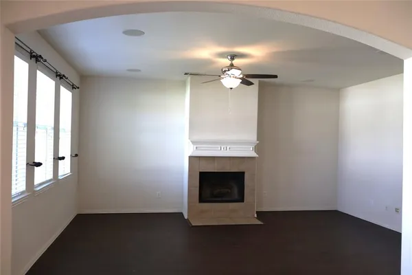 an empty room with a fireplace and chandelier fan
