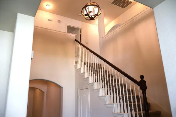 a view of staircase with railing and a chandelier