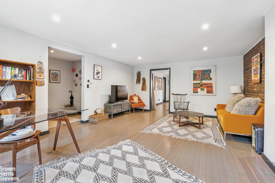 7 East 129th Street Manhattan, NY 10035 - Photo 21 of 24 a living room with furniture a wooden floor and a book shelf