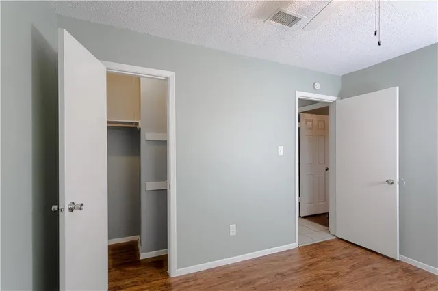 a view of an empty room with wooden floor and closet