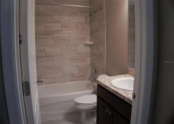 a bathroom with a granite countertop toilet a sink and bathtub