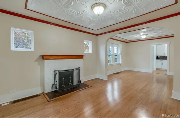 an empty room with wooden floor fireplace and windows