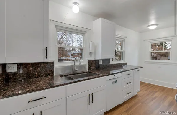 a kitchen with granite countertop a sink and white cabinets