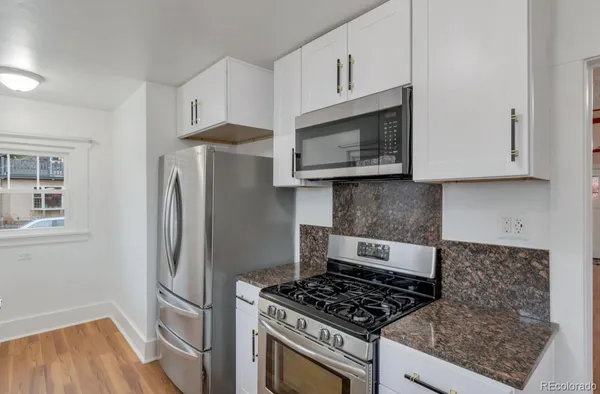 a kitchen with stainless steel appliances granite countertop a stove a microwave and a refrigerator