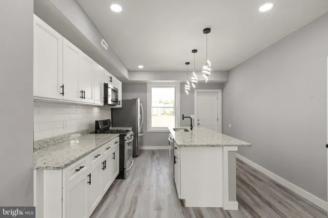 a kitchen with granite countertop cabinets a sink dishwasher and a stove with wooden floor