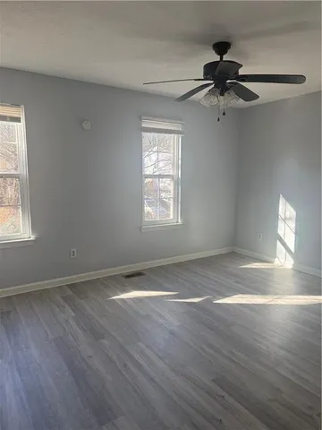 a view of an empty room with wooden floor and a window