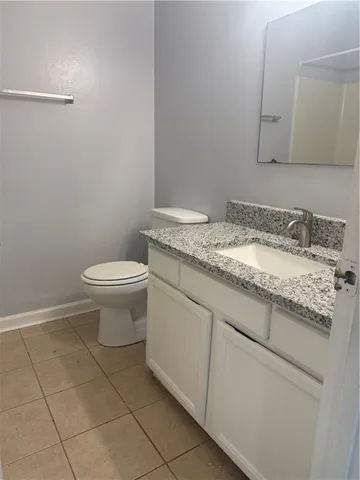 a bathroom with a granite countertop sink and a toilet