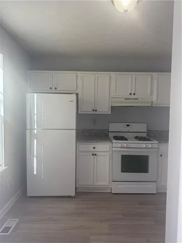 a kitchen with granite countertop white cabinets and white appliances