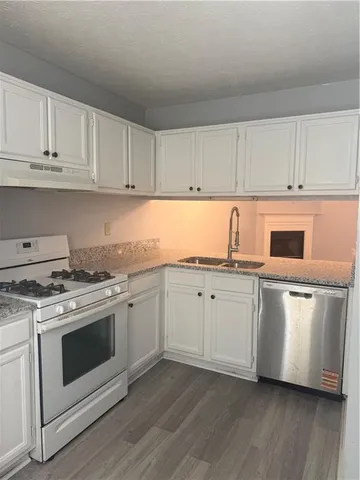 a kitchen with granite countertop white cabinets and white appliances