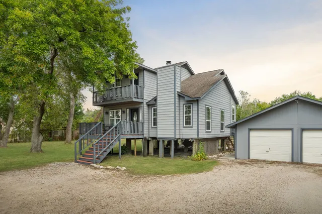 a view of a house with a yard and large tree