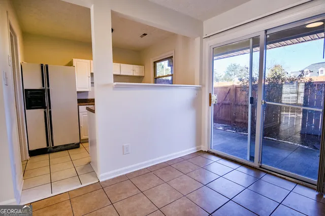 a view of a refrigerator in kitchen and an empty room in wooden floor