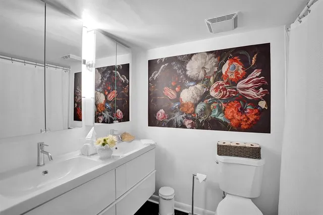 a bathroom with a sink mirror and a picture on the wall