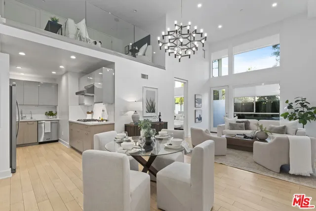 a living room with furniture kitchen view and a chandelier