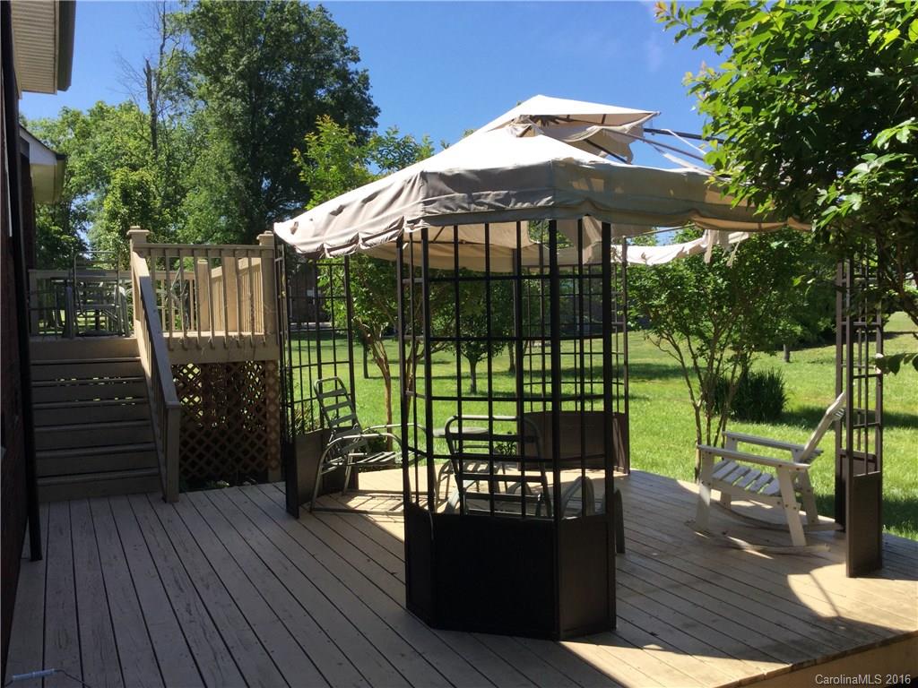 1906 Fletcher Broome Road Monroe, NC 28112 - Photo 3 of 15 a view of a deck with couches table and chairs under an umbrella with wooden floor